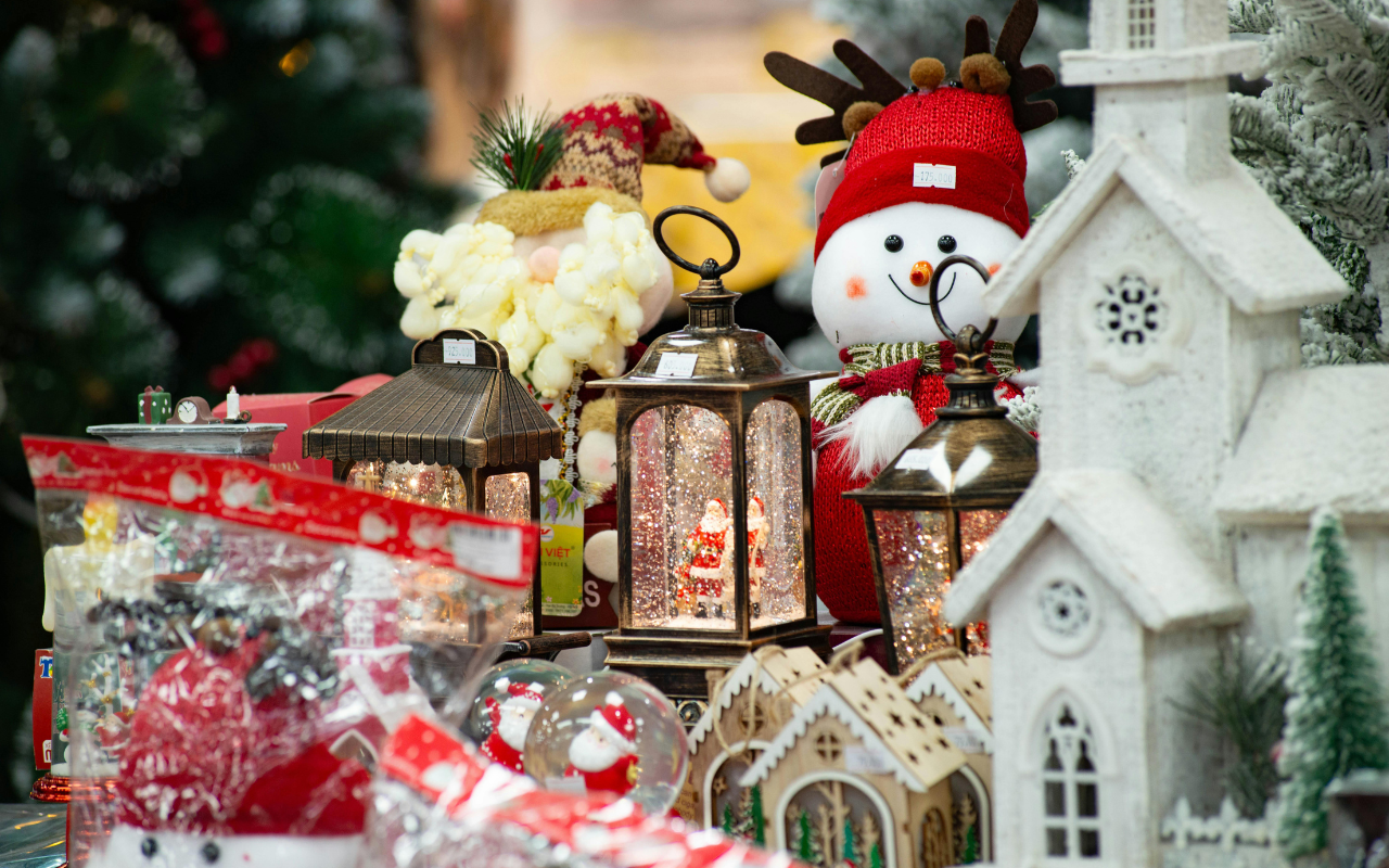 Christmas decorations including snowmen, lanterns, ornaments and festive figures displayed on a shop shelf.